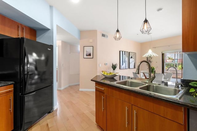 kitchen with pendant lighting, sink, light hardwood / wood-style flooring, and black fridge