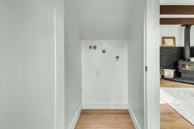 washroom featuring hookup for an electric dryer, light hardwood / wood-style floors, and a wood stove