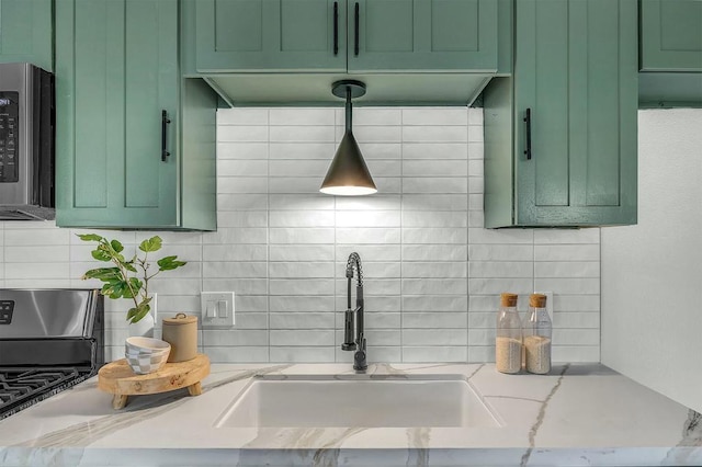 kitchen with green cabinets, light stone counters, sink, and decorative backsplash