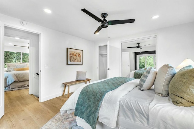 bedroom featuring a closet, light hardwood / wood-style floors, multiple windows, and ceiling fan