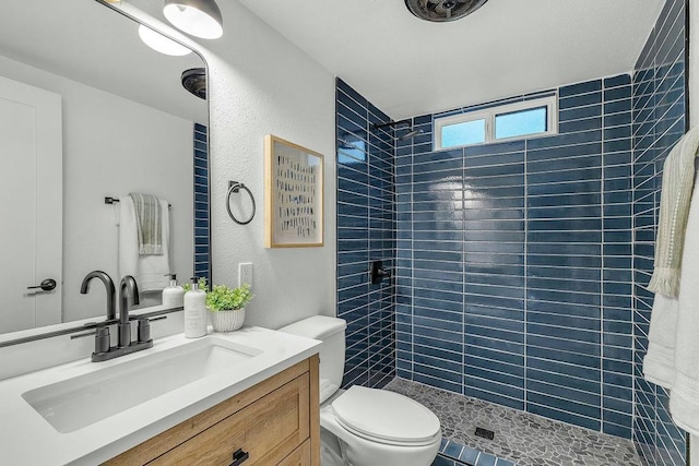 bathroom featuring tiled shower, vanity, and toilet