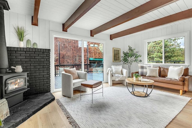 living room with beam ceiling, light wood-type flooring, and a wood stove