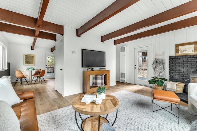 living room featuring beam ceiling, a wealth of natural light, and light hardwood / wood-style floors