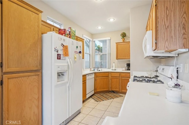 kitchen featuring light tile patterned floors, white appliances, and sink