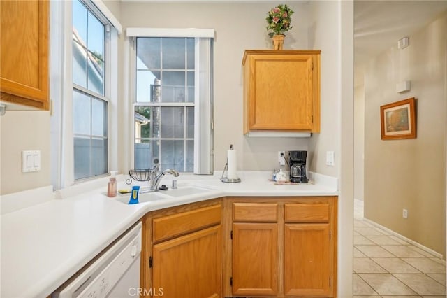 kitchen with light tile patterned floors, white dishwasher, and sink