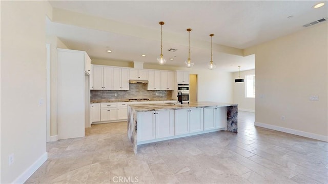 kitchen featuring a kitchen island with sink, sink, white cabinets, and hanging light fixtures