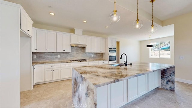 kitchen featuring white cabinets, an island with sink, and hanging light fixtures