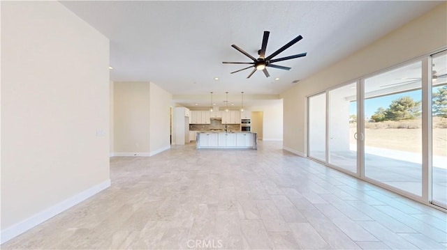 unfurnished living room featuring light hardwood / wood-style flooring, ceiling fan, and sink