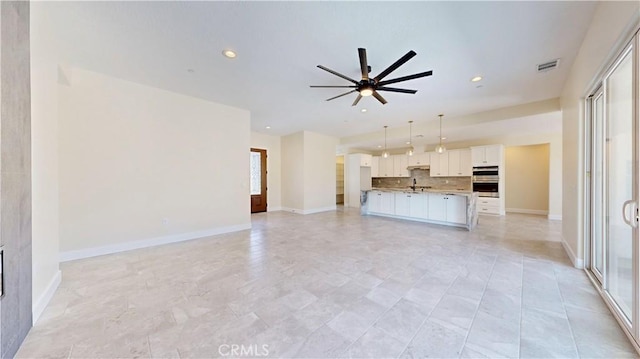 unfurnished living room with ceiling fan, plenty of natural light, and sink