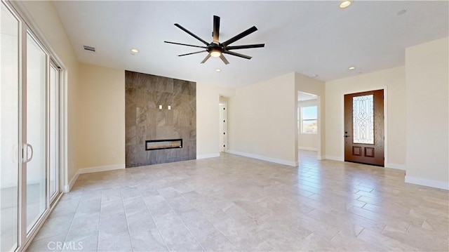 unfurnished living room featuring a tile fireplace and ceiling fan