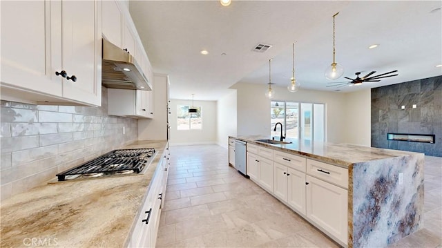 kitchen featuring light stone countertops, sink, white cabinets, and decorative light fixtures