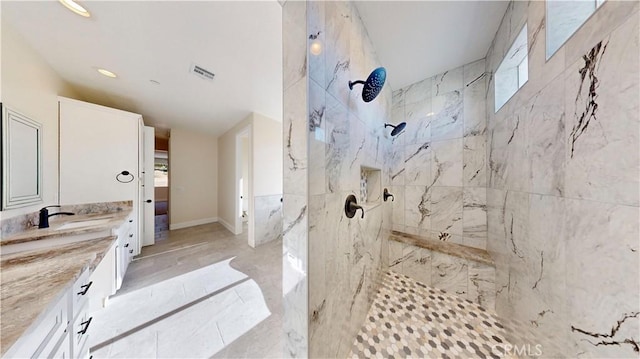 bathroom with a tile shower and vanity