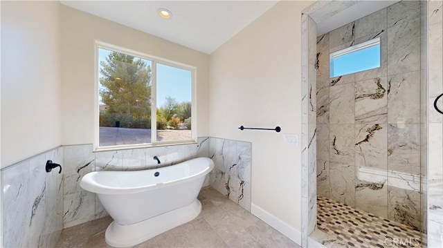 bathroom featuring plenty of natural light, lofted ceiling, and tile walls