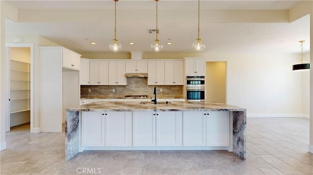 kitchen featuring appliances with stainless steel finishes, light stone counters, white cabinets, hanging light fixtures, and a large island