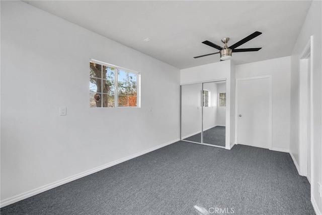 unfurnished bedroom with ceiling fan, a closet, and dark carpet