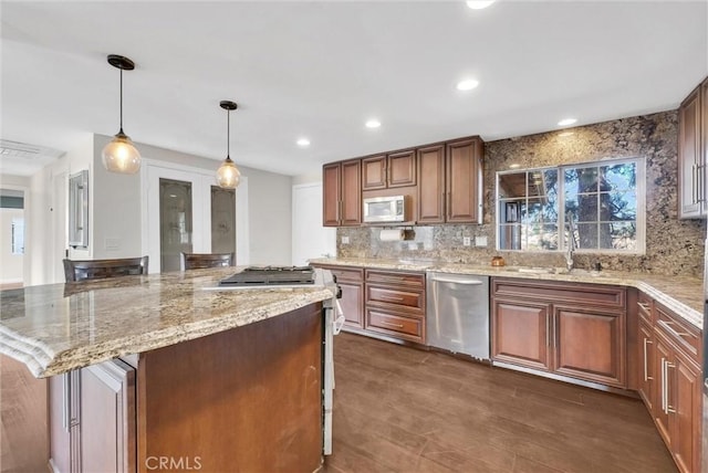 kitchen with hanging light fixtures, stainless steel appliances, light stone counters, dark hardwood / wood-style floors, and a kitchen island