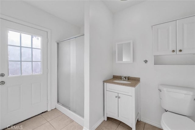 bathroom featuring tile patterned floors, vanity, a shower with shower door, and toilet