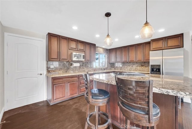 kitchen featuring stainless steel appliances, dark hardwood / wood-style flooring, pendant lighting, decorative backsplash, and a kitchen island