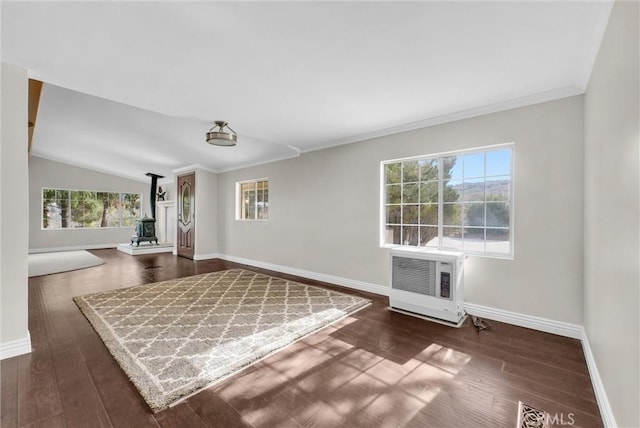 empty room with dark hardwood / wood-style floors, vaulted ceiling, a wood stove, and heating unit