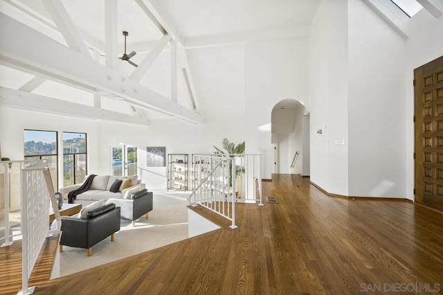 unfurnished living room featuring beam ceiling, ceiling fan, high vaulted ceiling, and dark hardwood / wood-style floors