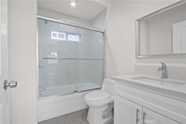 full bathroom featuring tile patterned floors, vanity, toilet, and shower / bath combination with glass door