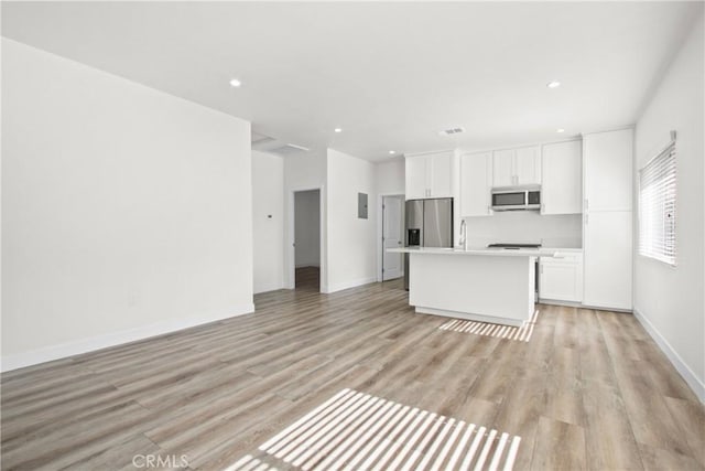 kitchen featuring white cabinets, appliances with stainless steel finishes, a center island, and light wood-type flooring