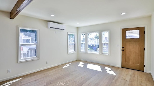 entrance foyer featuring beamed ceiling, an AC wall unit, and light hardwood / wood-style floors