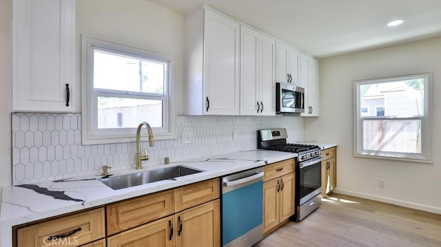 kitchen with stainless steel appliances, white cabinets, light stone counters, and decorative backsplash