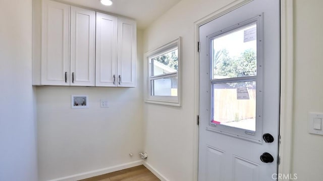 laundry room with washer hookup, wood-type flooring, and cabinets