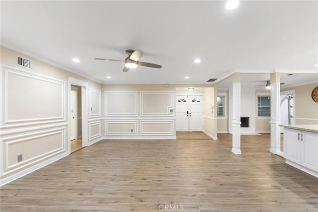 unfurnished living room with ceiling fan, ornamental molding, and light hardwood / wood-style flooring