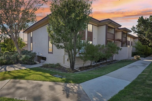 property exterior at dusk with a lawn