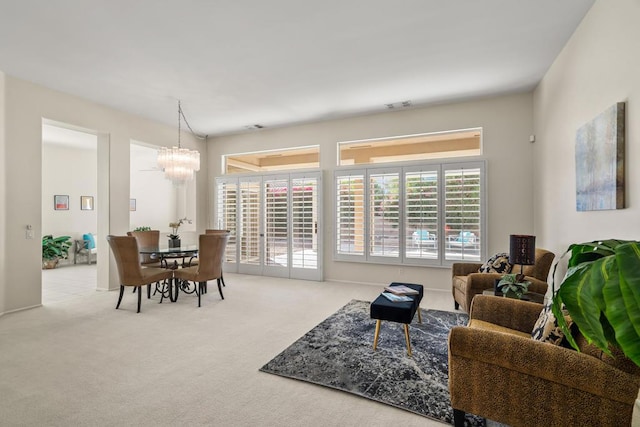 carpeted living room featuring an inviting chandelier