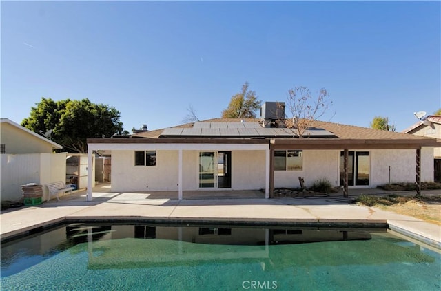 rear view of property featuring solar panels and a patio area