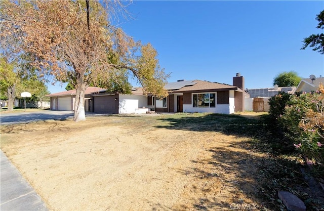 ranch-style home featuring solar panels, a garage, and a front lawn