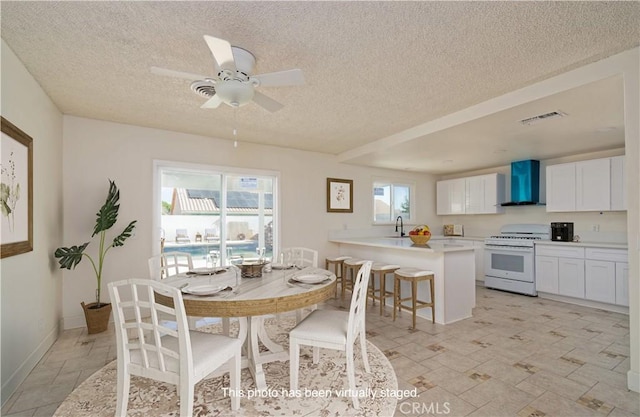 dining area with a textured ceiling, ceiling fan, and sink