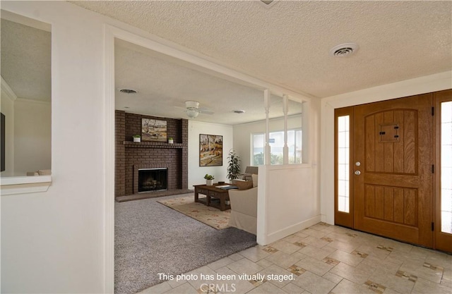 entrance foyer featuring a textured ceiling, ceiling fan, light carpet, and a brick fireplace