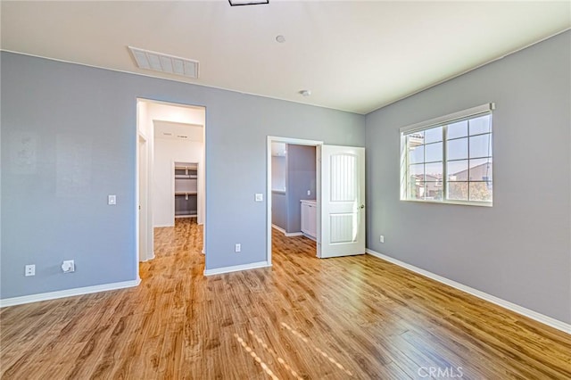 unfurnished bedroom with a walk in closet, light hardwood / wood-style flooring, and a closet