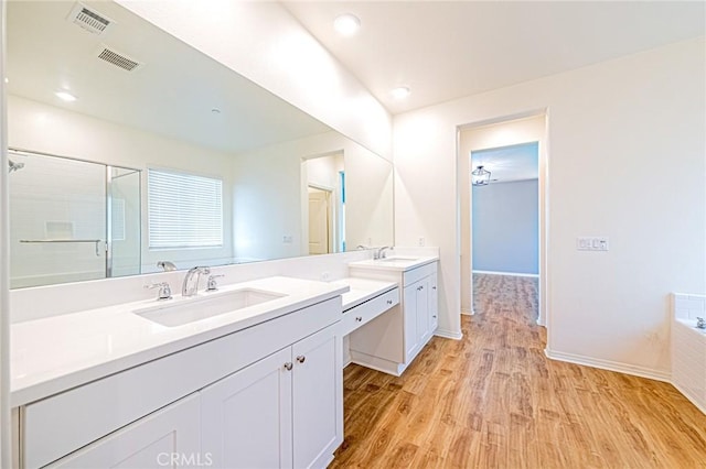 bathroom featuring vanity, hardwood / wood-style floors, and plus walk in shower