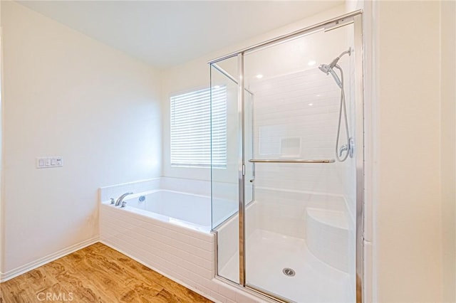 bathroom featuring wood-type flooring and shower with separate bathtub