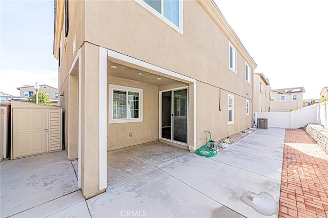 rear view of house with a storage unit, a patio, and central AC