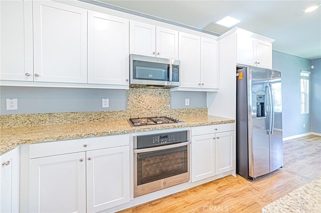 kitchen with white cabinetry, light hardwood / wood-style flooring, light stone counters, and appliances with stainless steel finishes