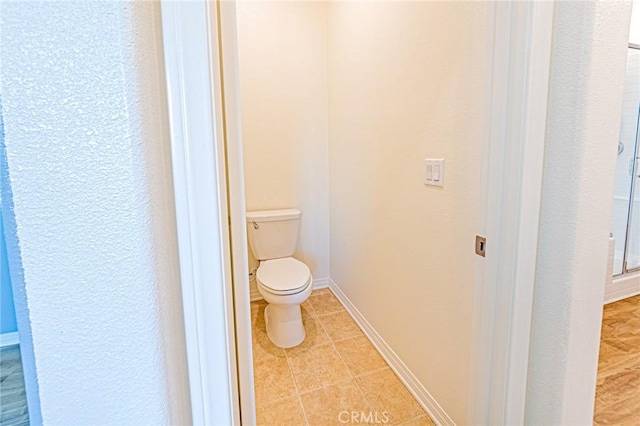 bathroom featuring tile patterned floors, toilet, and a shower with door