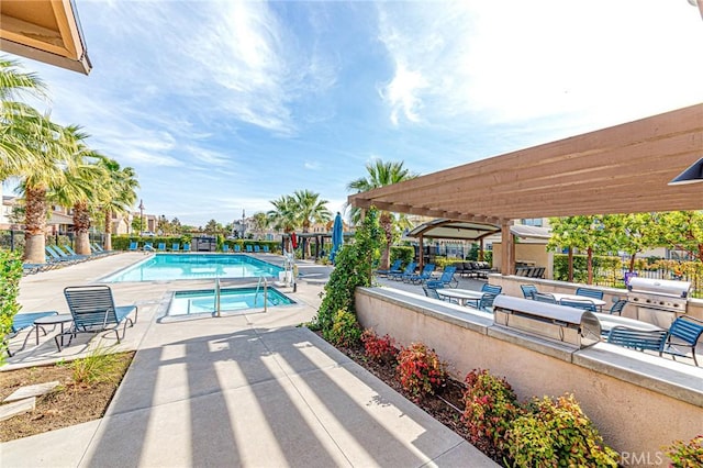 view of swimming pool featuring a pergola, area for grilling, a patio area, and exterior kitchen