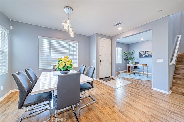 dining area with light hardwood / wood-style flooring and a chandelier