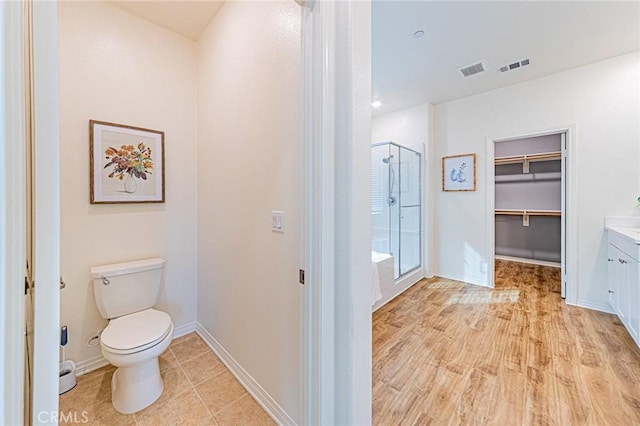 bathroom featuring hardwood / wood-style flooring, toilet, vanity, and an enclosed shower