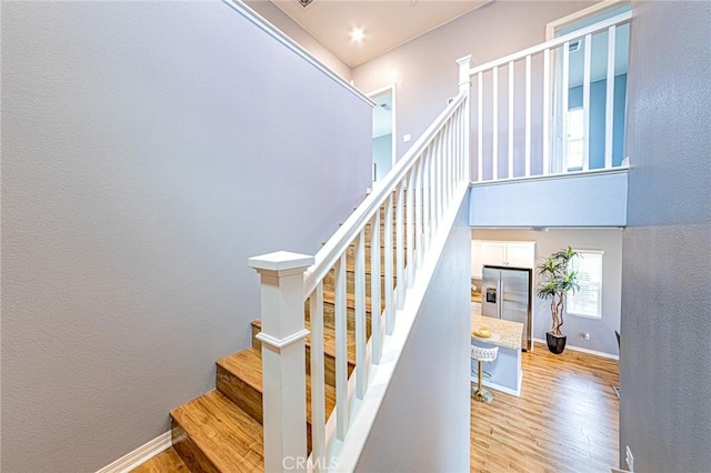 staircase with wood-type flooring and a towering ceiling