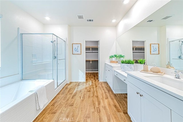 bathroom featuring plus walk in shower, vanity, and hardwood / wood-style floors