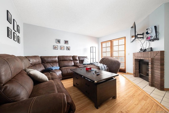 living room with a fireplace, a textured ceiling, and light wood-type flooring