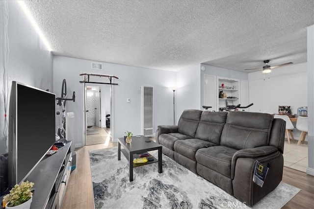 living room featuring ceiling fan, wood-type flooring, and a textured ceiling