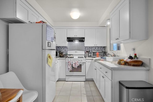 kitchen with decorative backsplash, white cabinetry, light tile patterned flooring, and white appliances